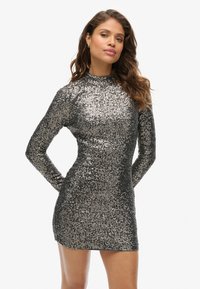 Kurzes, mit Pailletten besetztes Kleid in Schwarz und Silber mit langen Ärmeln, hohem Kragen und tailliertem Schnitt. Funkelnde Textur im gesamten Kleid.
