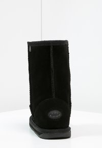 Stivale alla caviglia in suede nero con punta arrotondata, dettagli di cucitura sottili e suola in gomma. Presenta un logo circolare di EMU Australia sul tallone.