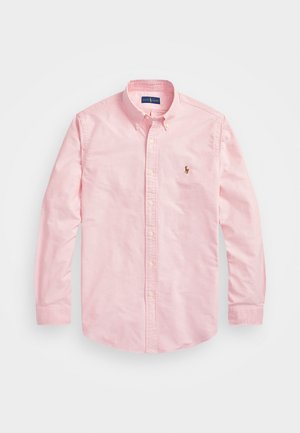 Camisa de botón de manga larga de color rosa claro en tela de algodón. Presenta un collar clásico, puños con botón y un pequeño logo bordado en el pecho.
