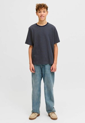 Marineblå og hvide stribede t-shirts med korte ærmer kombineret med lyseblå bukser med vide ben og beige slip-on sko. Simpelt, afslappet look.
