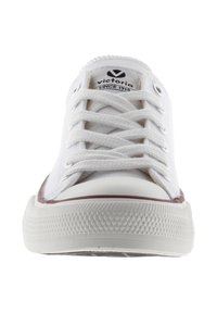 Sneakers bianchi in tela con punta tonda, bordi in gomma bordeaux a contrasto e lacci piatti. Logo visibile sulla linguetta. Suola in gomma testurizzata.