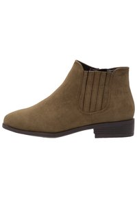Botas de tobillo de ante marrón con puntera afilada, paneles laterales elásticos y un tacón bajo en bloque. Presentan una textura suave y un diseño minimalista.