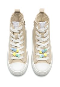 Zapatillas altas beige con cordones blancos, suelas de goma y cuentas decorativas en tonos pastel. Cuenta con material de lona texturizado y una pestaña en la parte posterior.