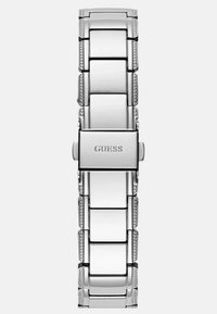 Zilveren armbandhorloge met een elegante metalen band, gekenmerkt door gepolijste schakels en textuurelementen. De sluiting is gegraveerd met "GUESS."