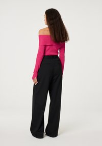 Off-the-shoulder roze trui met lange mouwen, gecombineerd met zwarte wijde broek. De trui heeft een zachte textuur en een aansluitend ontwerp.