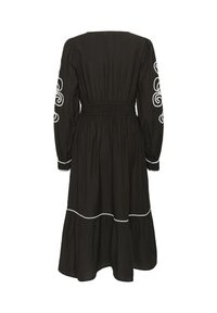 Černé šaty vyrobené z lehké tkaniny, s dlouhými rukávy zdobenými bílými vyšívanými víry a vrstveným lemem s bílým olemováním.