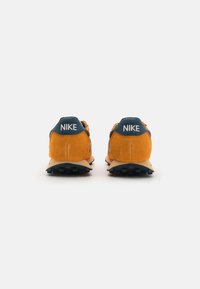 Nike tenisky s kombináciou oranžového semišu a námornícky modrej textílie, s gumovou podrážkou a bielym logom na päte.