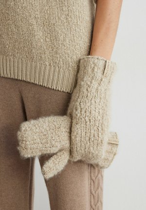 Beige gestrickte Fäustlinge aus strukturiertem Wollmaterial mit einem Akzentetikett. Weicher, flauschiger Stoff in lockerer, gemütlicher Form.