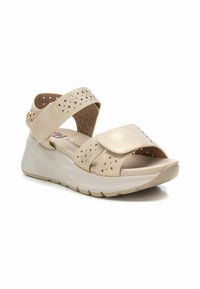 Sandalias de cuña beige con correas perforadas y cierre de Velcro. Suela ligera y plantilla suave para mayor comodidad. Textura suave, diseño minimalista.