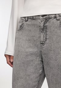 Jeans in denim grigio con una finitura sbiadita, design a gamba dritta, stile a cinque tasche e chiusura con bottone in vita.