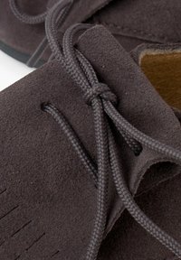 Zapatos informales de ante marrón con parte superior texturizada, costuras decorativas y cordones trenzados, con un forro interior suave.
