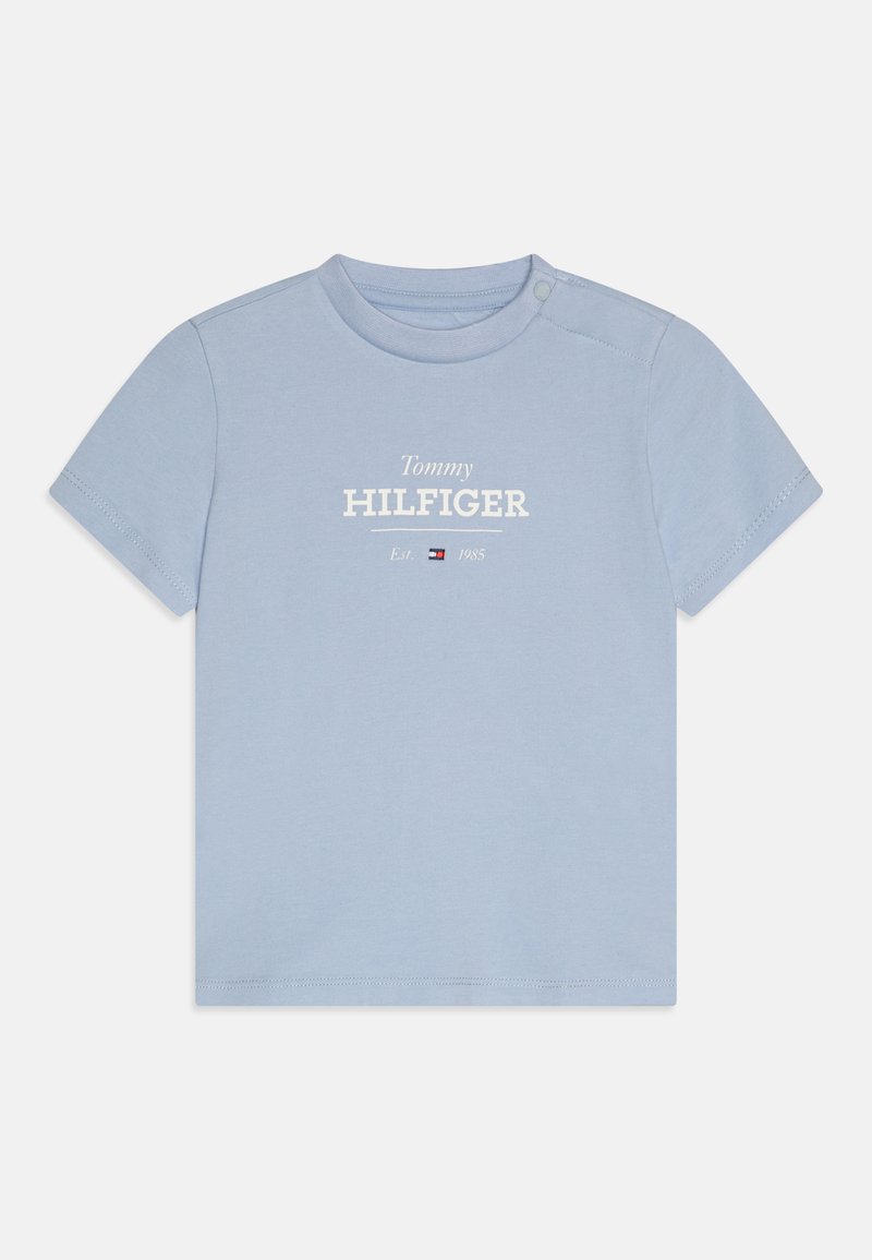 Svetlo modra kratka majica z kratkimi rokavi iz bombaža. Ima bel logo "Tommy HILFIGER" z letnico ustanovitve in grbom. Zapiranje z gumbom na rami.