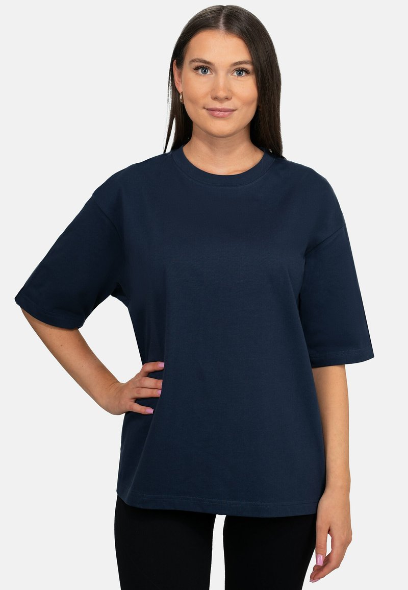 T-shirt en coton bleu marine avec des manches courtes, un col rond et une coupe décontractée, présenté sur un modèle devant un fond blanc uni.