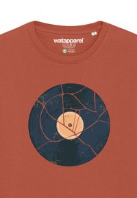 Roestkleurig t-shirt met een afbeelding van een gebroken vinylplaat met een beige label en zwarte groeven in het midden.