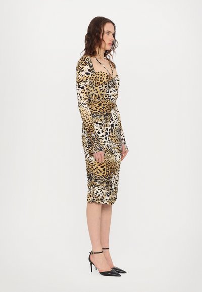 Leopard print dress with long sleeves, fitted silhouette, ruched texture, and a knee-length hem. Paired with black high-heel shoes.