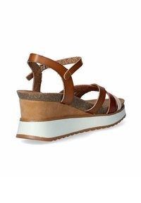Sandalias de cuña de cuero marrón con múltiples correas, plantilla de corcho y una suela blanca. El tacón contorneado mejora la estabilidad y el soporte.