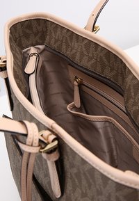 Sac à main brun à motif avec un intérieur beige, comportant une poche zippée et deux compartiments intérieurs, des doubles anses et des accents en métal doré.