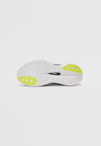 Suela de zapatilla blanca con una textura estampada; presenta acentos de goma amarilla y un logotipo de la marca en negro.