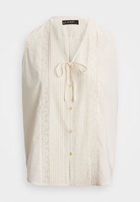 Cream-colored blouse with a v-neck, tied ribbon, lace accents, and vertical pleats. Features buttons down the front and delicate embroidery.
