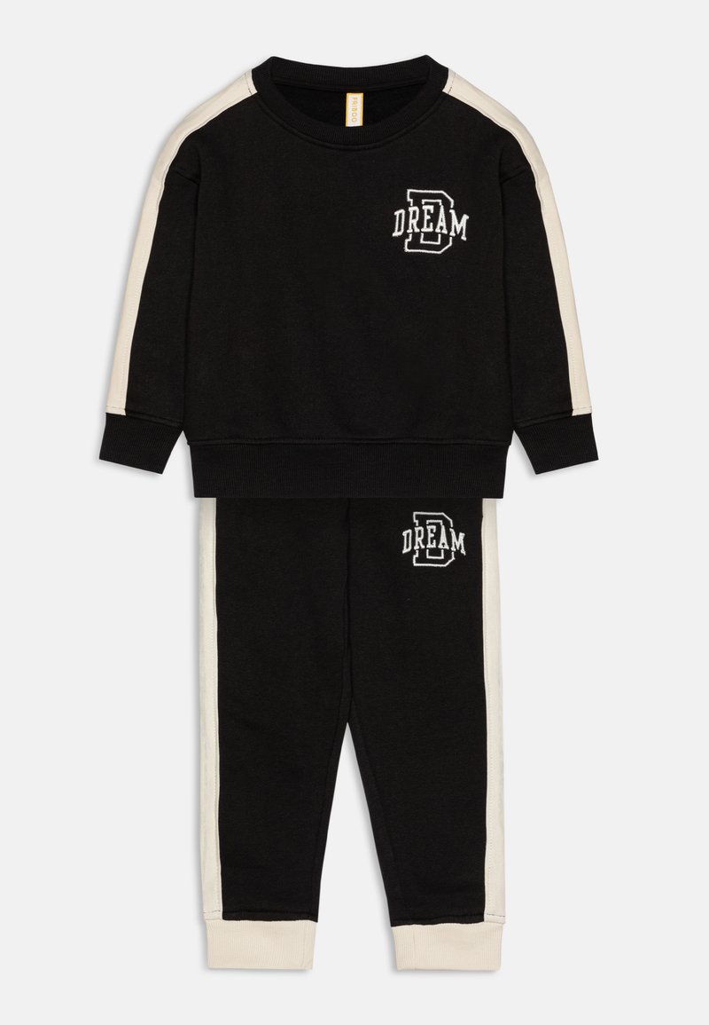 Black sweatshirt and pants set with cream side stripes. Sweatshirt features "DREAM" embroidered on the front. Soft, textured fabric.