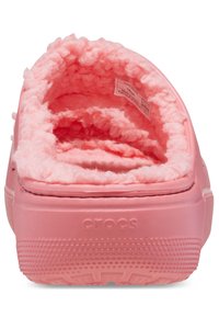 Różowe klapki Crocs z miękkim, puszystym wnętrzem. Posiadają zaokrąglony, otwarty tył, gumową podeszwę oraz teksturowane dno zapewniające przyczepność.