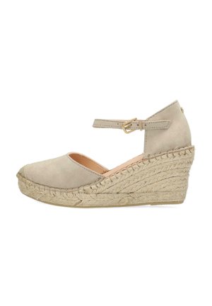 Beige suede wedge shoe with a round toe, ankle strap with buckle, and jute-wrapped heel. Features a smooth upper and textured sole.