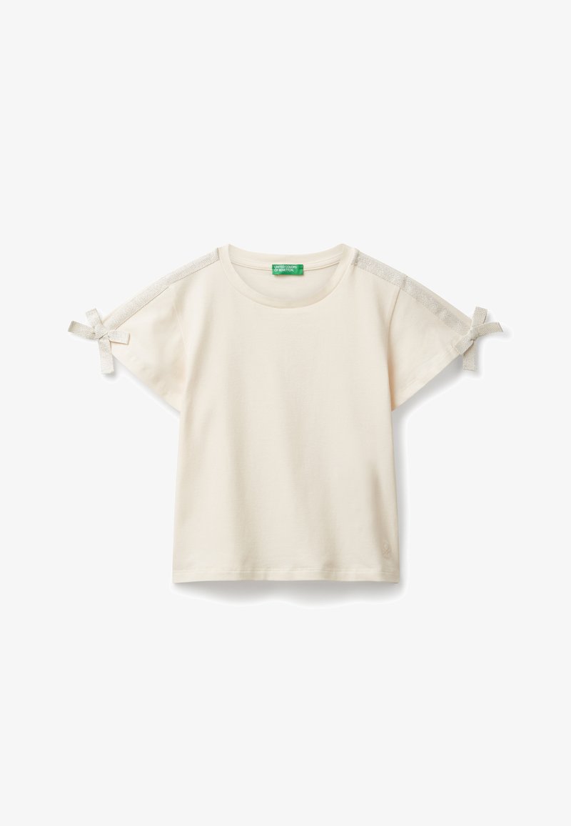 Krémové tričko s krátkým rukávem a kulatým výstřihem, dekorativní strukturovaná páska podél ramen a uvázané mašle na koncích rukávů.