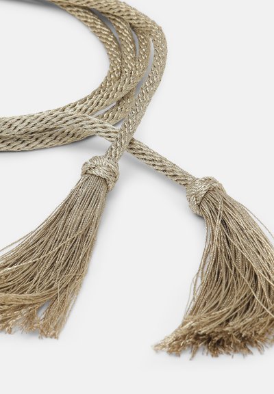 Corda dorata intrecciata con pompom a entrambe le estremità. La texture è liscia e lucida, con un colore oro uniforme in tutto il design.