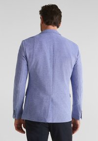 Light blue blazer made of textured fabric, featuring a single vent at the back, notched lapels, and buttoned cuffs.