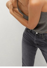 Top de tirantes gris con perfilado, ajustado, de una sola cinta. Vaqueros de cintura alta gris oscuro con un diseño clásico de cinco bolsillos y ligeros desgastes.