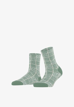 Een paar groene enkelsokken met witte golvende lijnpatronen die in abstracte rechthoekige vormen zijn gerangschikt, met effen groen bij de tenen en hielen.