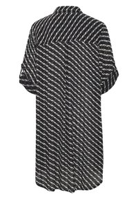 Blouse noir et blanc à manches courtes avec col, arborant un motif abstrait diagonal répétitif et une coupe ample.