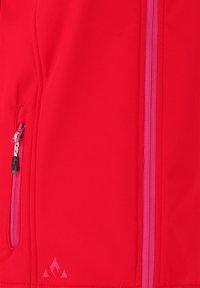 Röd softshell-jacka med en sidoficka med rosa dragkedja, texturerad tyg och en diskret logga längst ner.