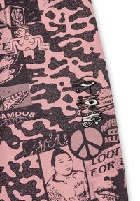 Textile featuring a pink and black collage design with animal prints, graphic illustrations, text, and embroidered accents of eyes and symbols.