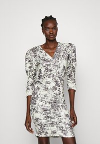 Gemustertes Kleid in Hellgrün mit abstraktem Druck in Dunkelgrau. Mit Puffärmeln, V-Ausschnitt und gerafftem Material in der gesamten Verarbeitung.