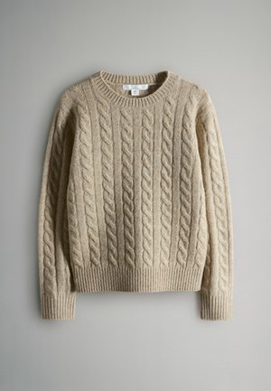 Béžový svetr s pleteným vzorem a žebrovaným výstřihem a manžetami. Obsahuje strukturovaný vzor se zvýšenými kabely, které se vertikálně táhnou po látce.