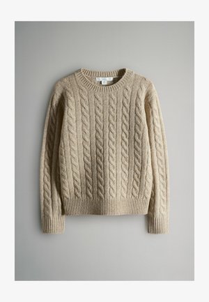 Béžový sveter z pleteného vzoru s rebrovaným výstrihom a manžetami. Má textúrovaný vzor s vystúpenými káblami, ktoré sa vertikálne tiahnu cez materiál.