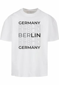 Hvit bomulls t-skjorte med dristig tekstdesign: "TYSKLAND" og "BERLIN" i ulike skrifttyper og nyanser av grått, sentral plassering, kort erm.