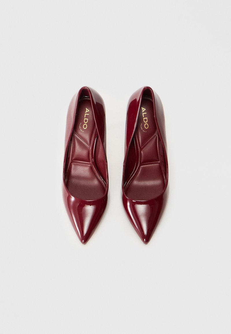 Décolleté a punta in materiale sintetico borgogna lucido con una superficie liscia e un design aperto nella parte frontale. Logo del marchio visibile all'interno.