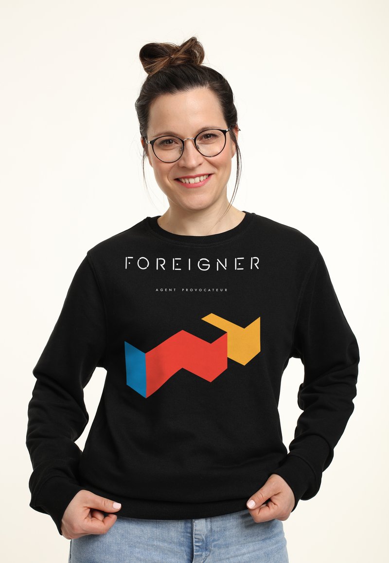 Felpa nera con un design grafico audace. Presenta la parola "FOREIGNER" in bianco e un motivo geometrico rosso, blu e giallo sulla parte frontale.