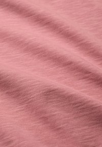 Miękki, jasnoróżowy materiał o subtelnej fakturze i gęstym, równomiernym splocie, ułożony w taki sposób, aby pokazać fałdy i kontury.