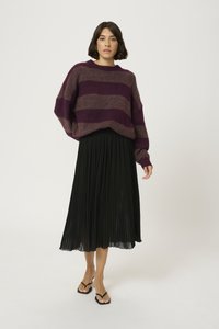 Üks suur lilla ja hall triibuline sviiter pehmest kudumisest, mis on kombineeritud musta volditud midi-seeliku ja mustade lamedate sandaalidega.