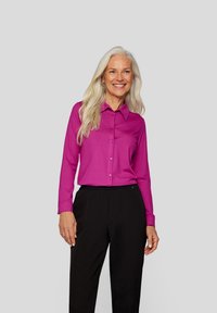 Fuchsia button-up shirt with a collar and long sleeves, paired with black pants. Smooth texture, minimalistic design, no visible patterns.