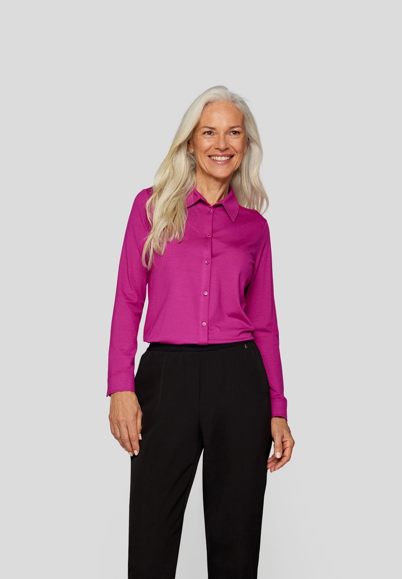 Fuchsia button-up shirt with a collar and long sleeves, paired with black pants. Smooth texture, minimalistic design, no visible patterns.