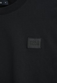 Czarna bluza z ribbowym dekoltem i teksturowaną czarną łatą z napisem "POLO CLUB" z przodu. Miękka tkanina i dopasowany krój.