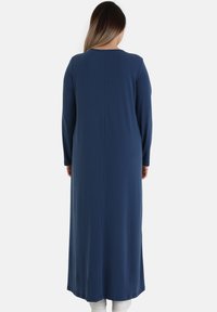 Long-sleeved, navy blue dress made of smooth fabric. Features a straight silhouette with a rounded neckline and a back seam detail.