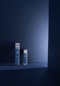 Dos cortaúñas de metal con agarres de goma azul, con una superficie texturizada, colocados sobre un fondo oscuro con iluminación suave.