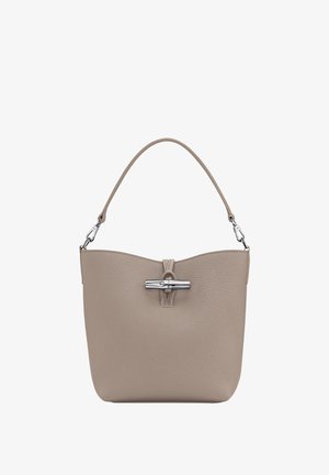 Beige leather handbag with a smooth texture, curved top, and a silver-tone clasp detail. Features a single shoulder strap.