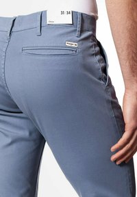 Niebieskie spodnie chino wykonane z gładkiego materiału, z bocznymi i tylnymi kieszeniami oraz małą metką Wrangler z tyłu. Rozmiar w talii 31, długość 34.