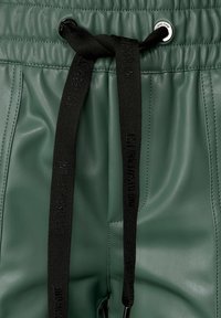 Vihreät nahkaverkkarit mustalla nyörillä, jossa on kohokirjoitus. Mukana metallinen reikään ja sileä, pehmeä pinta.